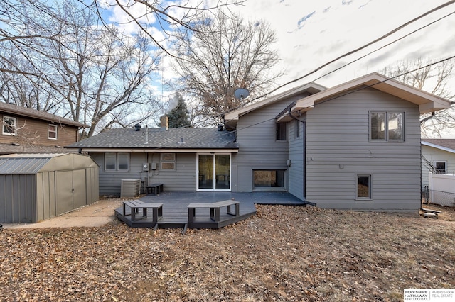 rear view of house featuring a deck, cooling unit, and a shed