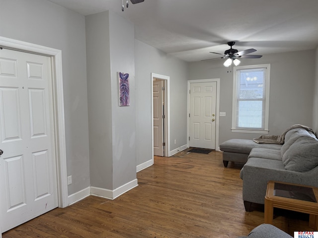 living room featuring dark wood finished floors, a ceiling fan, and baseboards