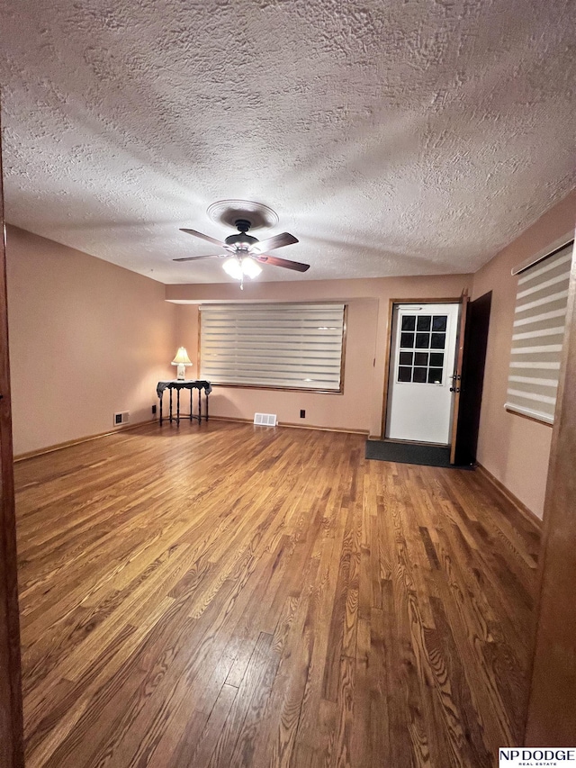 unfurnished living room with a textured ceiling and wood-type flooring