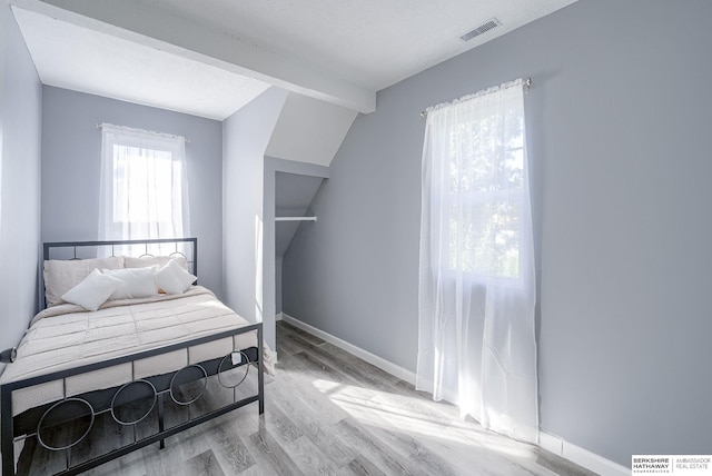 bedroom featuring vaulted ceiling and light hardwood / wood-style flooring