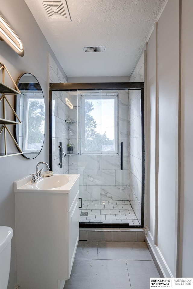 bathroom featuring tile patterned floors, a healthy amount of sunlight, toilet, and a textured ceiling