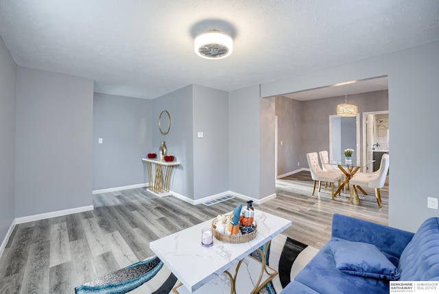 living room featuring hardwood / wood-style floors, a textured ceiling, and a notable chandelier