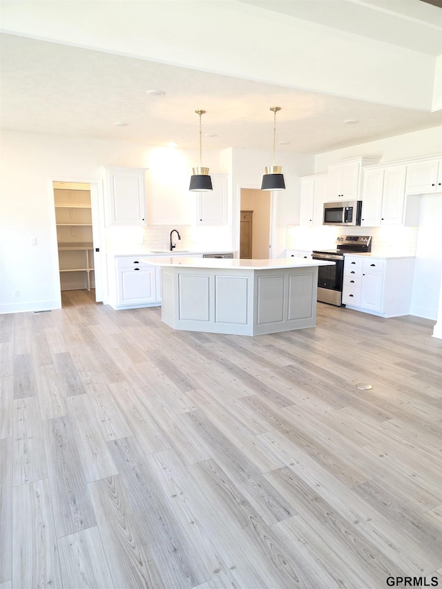 kitchen featuring light wood finished floors, white cabinetry, stainless steel appliances, and light countertops