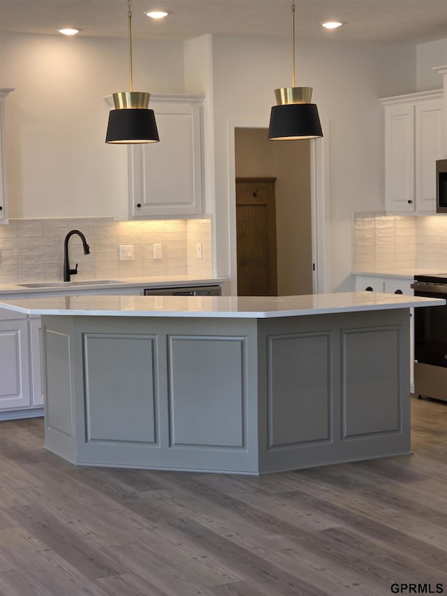 kitchen featuring a sink, stove, light countertops, white cabinets, and stainless steel microwave