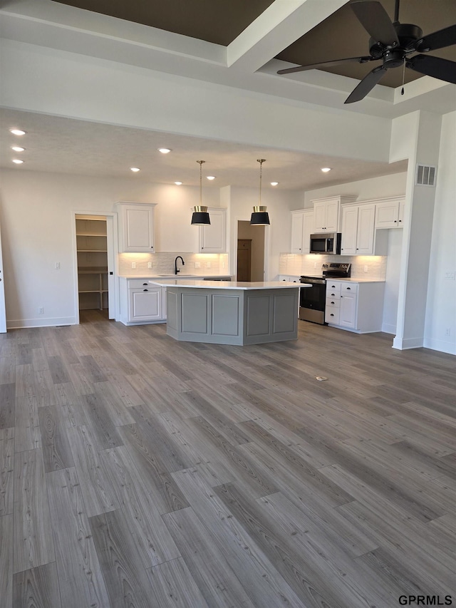 kitchen featuring wood finished floors, visible vents, decorative backsplash, light countertops, and appliances with stainless steel finishes