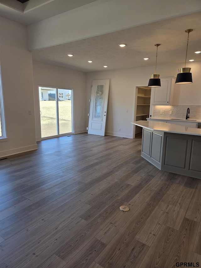 kitchen featuring backsplash, white cabinetry, light countertops, and dark wood-style flooring