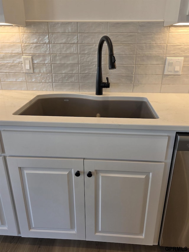 details with decorative backsplash, white cabinets, dishwasher, and a sink