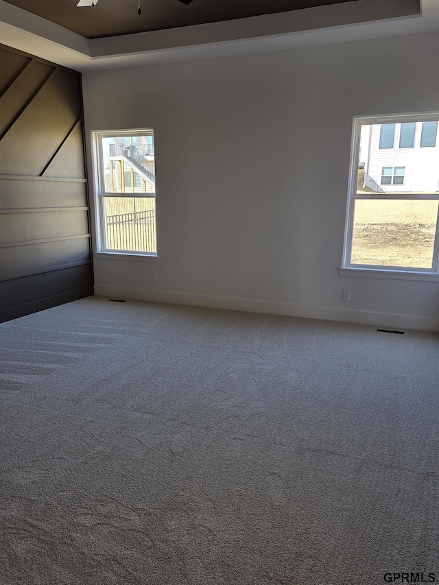 empty room with baseboards, visible vents, and carpet floors