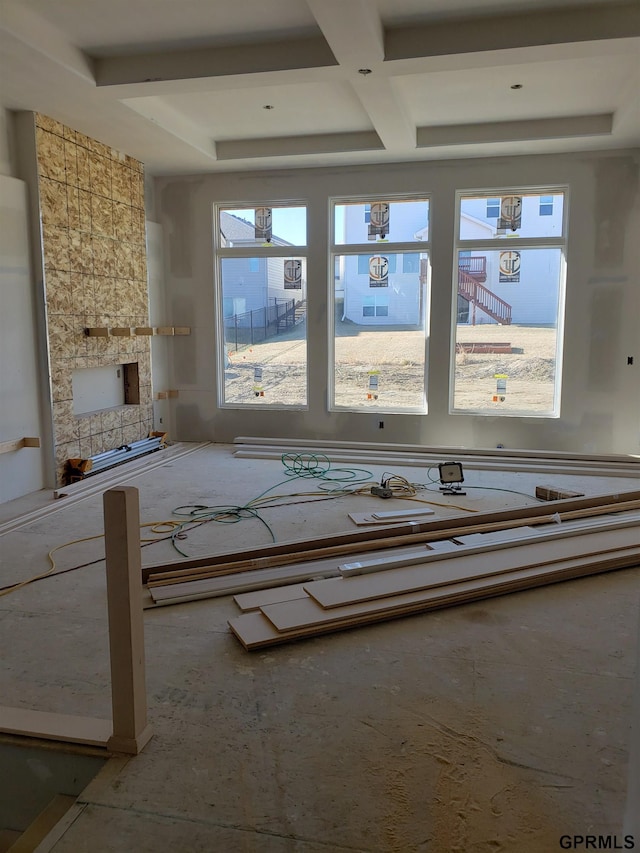 unfurnished living room with beamed ceiling, coffered ceiling, and a healthy amount of sunlight