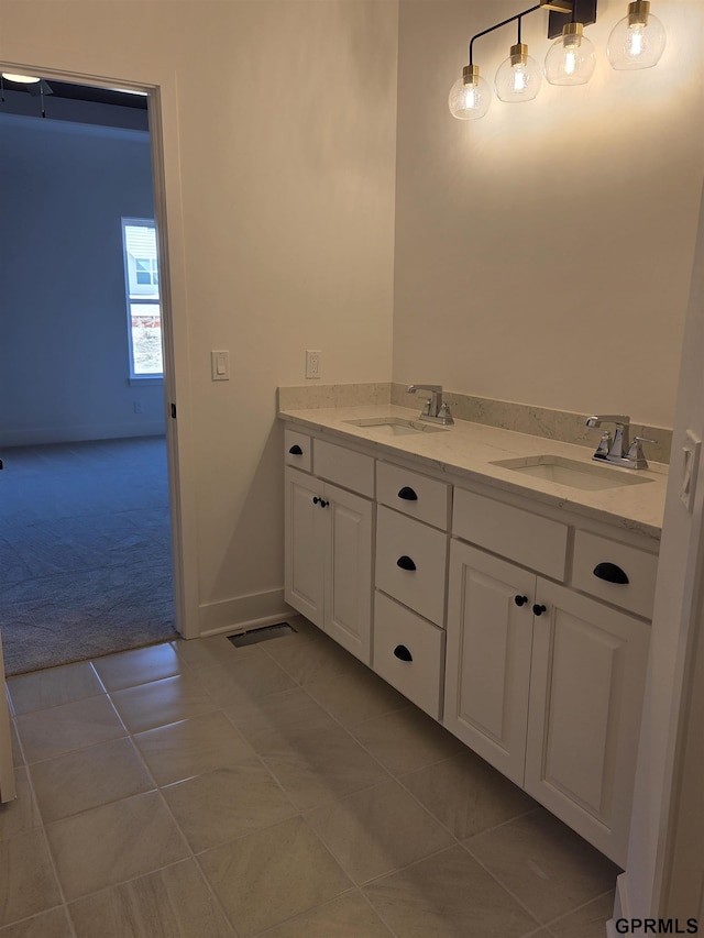 bathroom featuring tile patterned flooring, double vanity, baseboards, and a sink