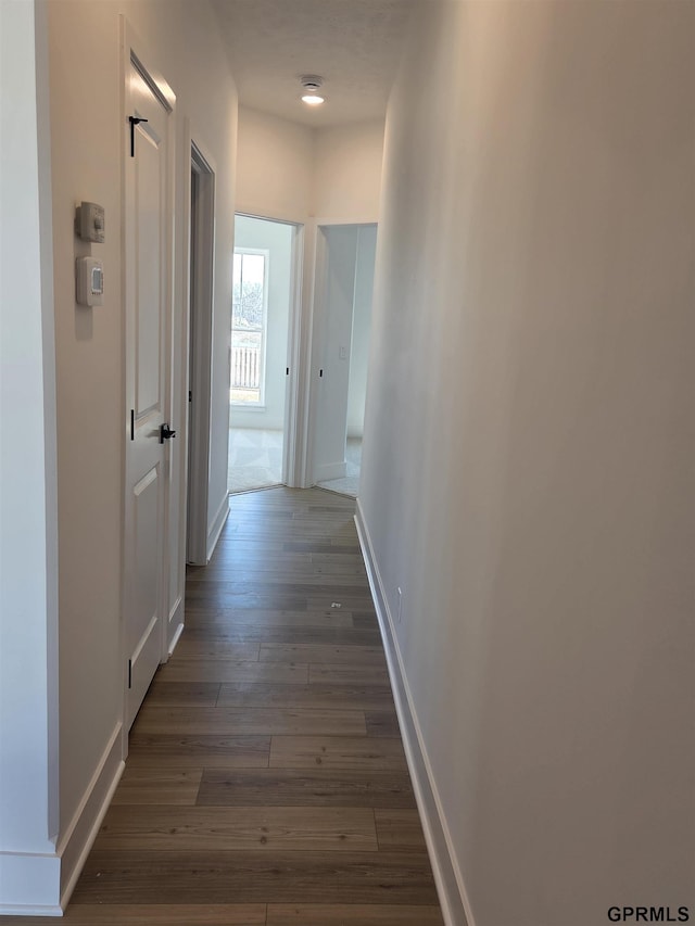 corridor featuring wood finished floors and baseboards