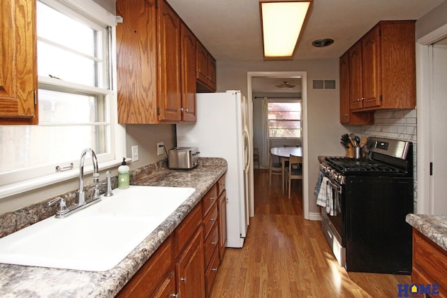 kitchen featuring stainless steel gas stove, light wood-type flooring, plenty of natural light, and sink