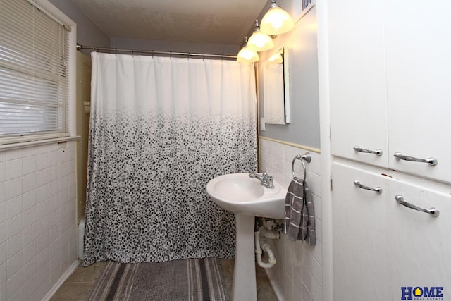 bathroom with tile patterned flooring, shower / bathtub combination with curtain, and tile walls