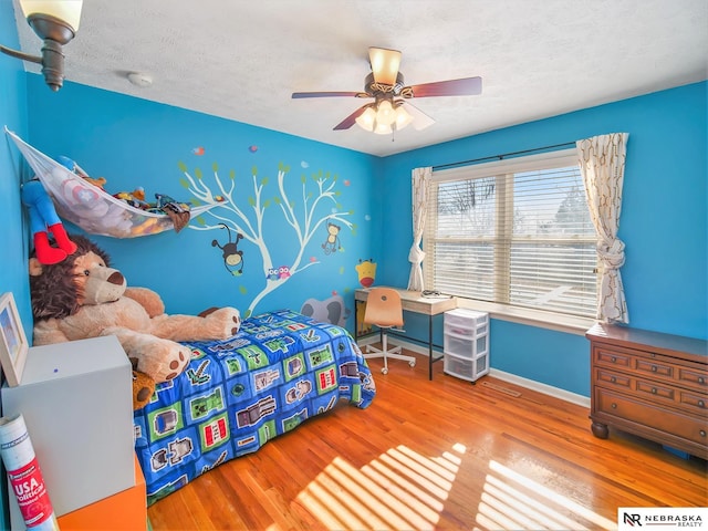 bedroom featuring hardwood / wood-style flooring, ceiling fan, and a textured ceiling