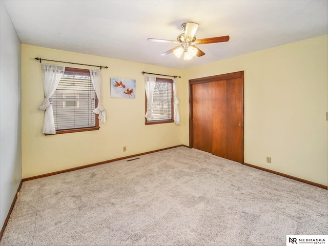 unfurnished bedroom with ceiling fan, multiple windows, light colored carpet, and a closet