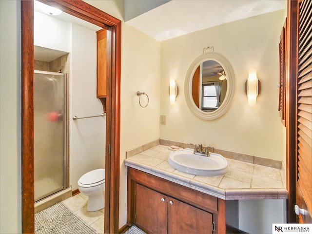 bathroom featuring a shower with door, vanity, tile patterned flooring, and toilet