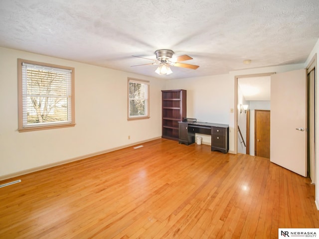 interior space with ceiling fan, a textured ceiling, and light wood-type flooring