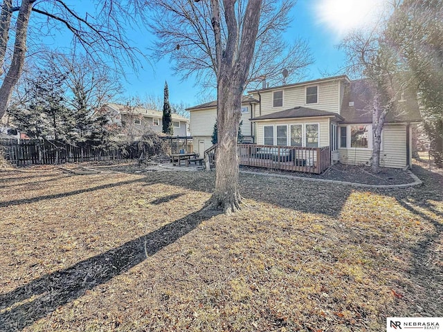 back of property with a wooden deck and a lawn