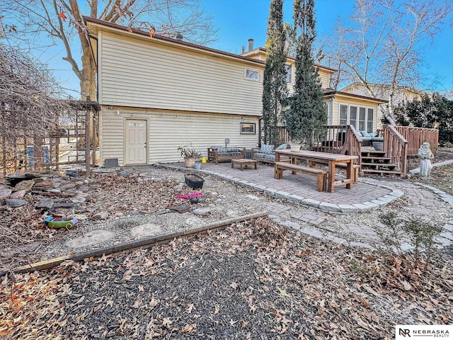 back of house featuring a wooden deck and a patio