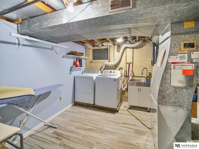 clothes washing area with independent washer and dryer and sink