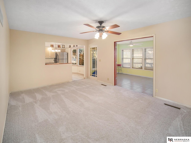 unfurnished room featuring ceiling fan, light colored carpet, and a textured ceiling