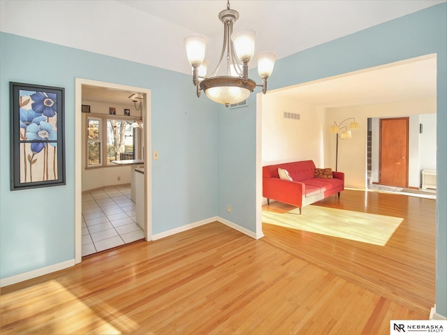 spare room with hardwood / wood-style floors and a notable chandelier