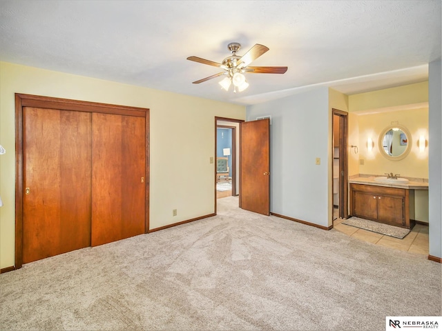 unfurnished bedroom with sink, light colored carpet, a closet, and ensuite bathroom