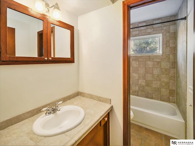 full bathroom featuring vanity, tiled shower / bath, and toilet