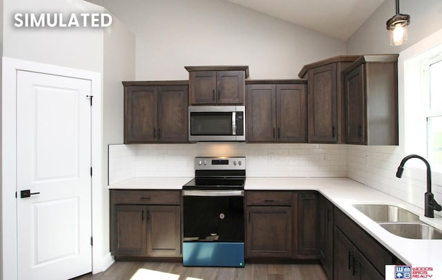 kitchen featuring lofted ceiling, sink, decorative backsplash, appliances with stainless steel finishes, and dark brown cabinetry