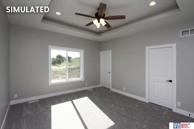 carpeted empty room featuring a raised ceiling and ceiling fan