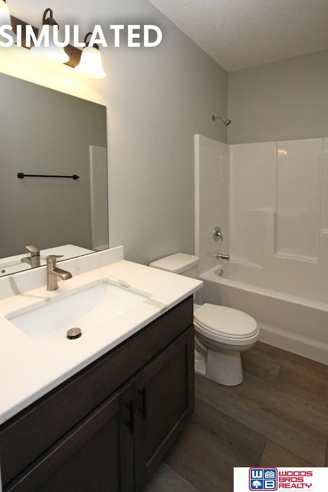 full bathroom with hardwood / wood-style floors, vanity, toilet, a textured ceiling, and tub / shower combination