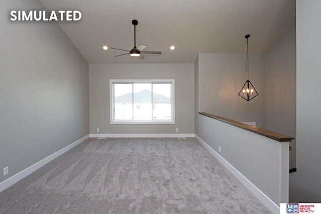 empty room with ceiling fan with notable chandelier, carpet floors, and lofted ceiling