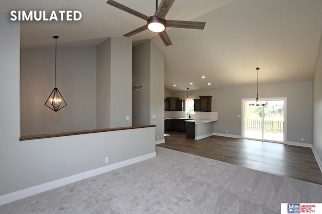 unfurnished living room featuring dark colored carpet, vaulted ceiling, ceiling fan, and sink