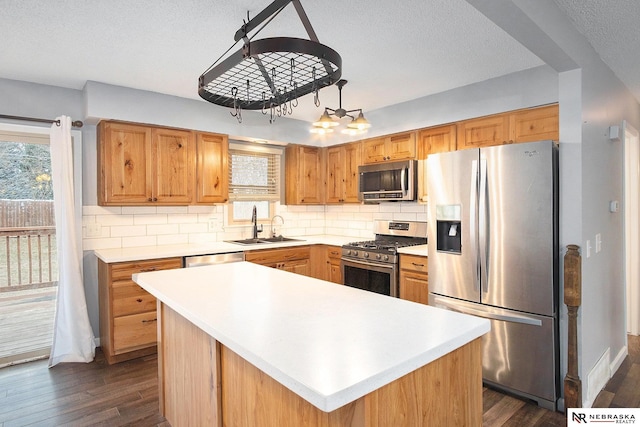 kitchen featuring appliances with stainless steel finishes, a kitchen island, plenty of natural light, and sink