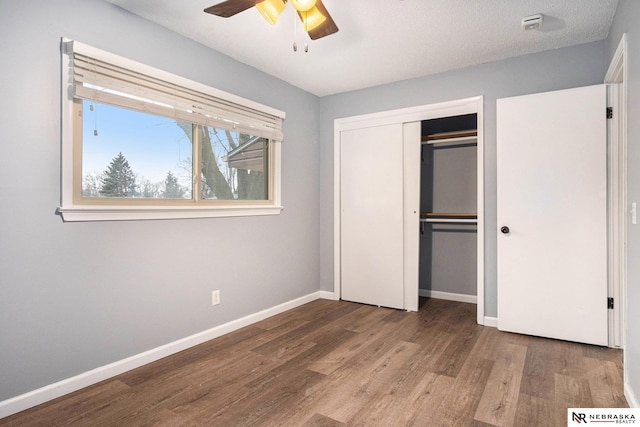 unfurnished bedroom featuring ceiling fan, a closet, wood-type flooring, and a textured ceiling