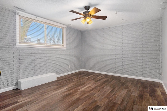 unfurnished room featuring dark hardwood / wood-style flooring and brick wall