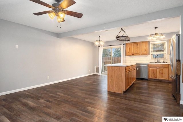 kitchen featuring kitchen peninsula, tasteful backsplash, stainless steel appliances, sink, and hanging light fixtures