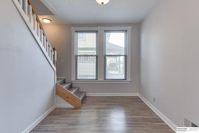 stairway featuring wood-type flooring and a textured ceiling