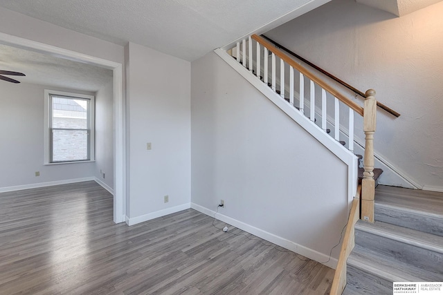 stairs with wood-type flooring, a textured ceiling, and ceiling fan