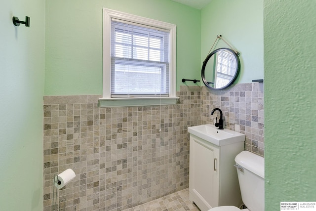 bathroom featuring vanity, toilet, and tile walls