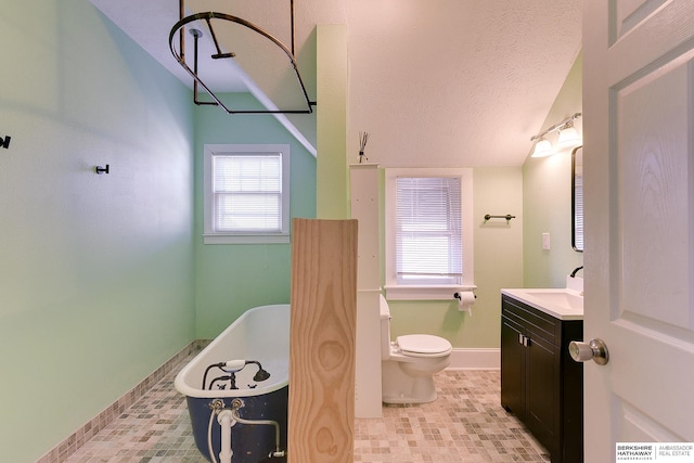 bathroom with vanity, a bathtub, a textured ceiling, and toilet