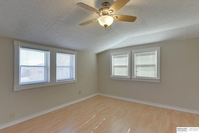 unfurnished room with light wood-type flooring, a textured ceiling, vaulted ceiling, and ceiling fan