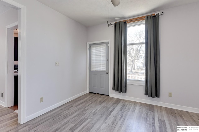 empty room with ceiling fan, light hardwood / wood-style floors, and a textured ceiling