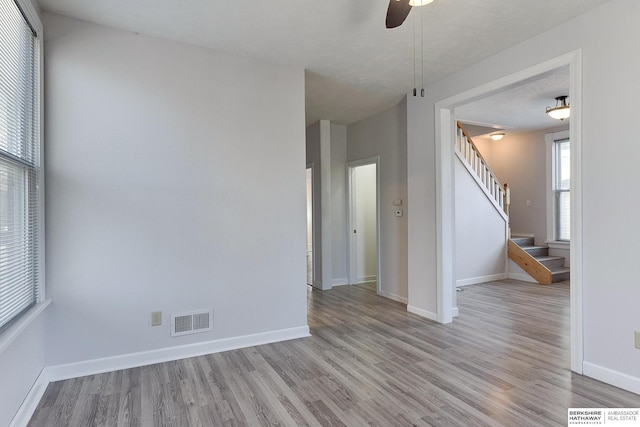 unfurnished room with ceiling fan, a textured ceiling, and light wood-type flooring