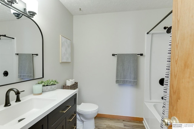 full bathroom with hardwood / wood-style floors, vanity, shower / tub combination, toilet, and a textured ceiling