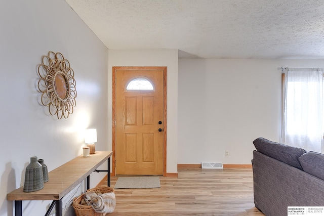 entryway with plenty of natural light, light hardwood / wood-style floors, and a textured ceiling