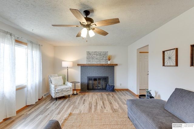 unfurnished living room with a fireplace, a textured ceiling, light hardwood / wood-style flooring, and plenty of natural light