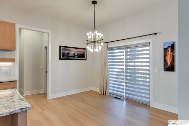 unfurnished dining area with light wood-type flooring and an inviting chandelier