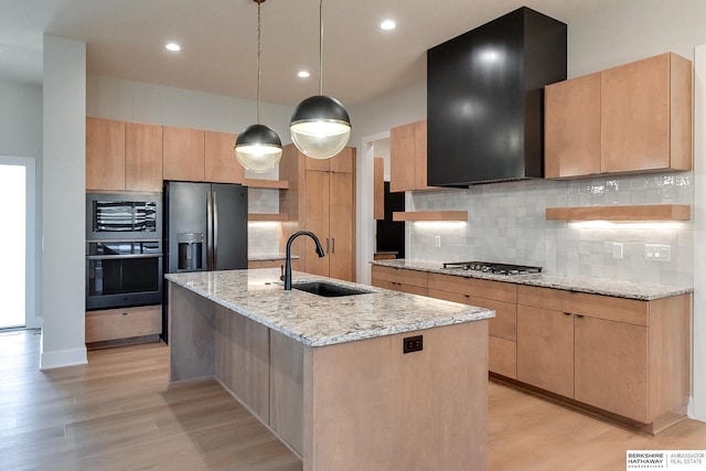 kitchen with sink, backsplash, a kitchen island with sink, exhaust hood, and appliances with stainless steel finishes