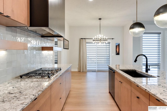 kitchen featuring appliances with stainless steel finishes, light stone counters, pendant lighting, and sink